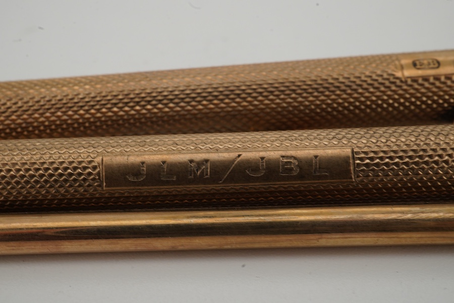 Two engine turned 9ct gold cased pencils including smallest by Sampson Mordan & Co, hallmarked for London, 1937, 7cm, the smaller with engraved inscription, together with a gold plated swizzle stick, larger pencil by E.